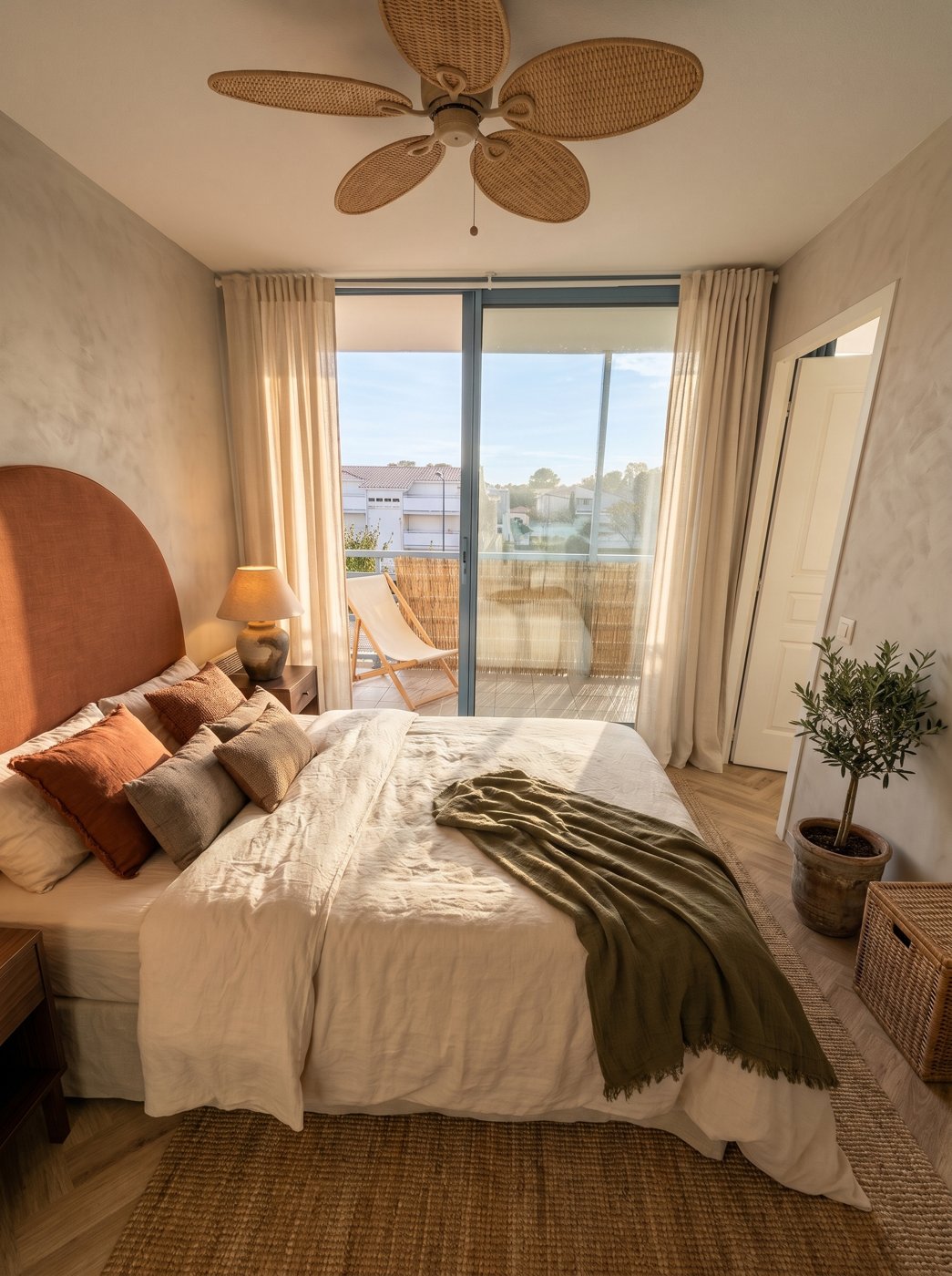 Projection de la chambre de La Casa : tête de lit arrondie terracotta, linge en lin crème, plaid olive, baie vitrée ouverte sur la terrasse