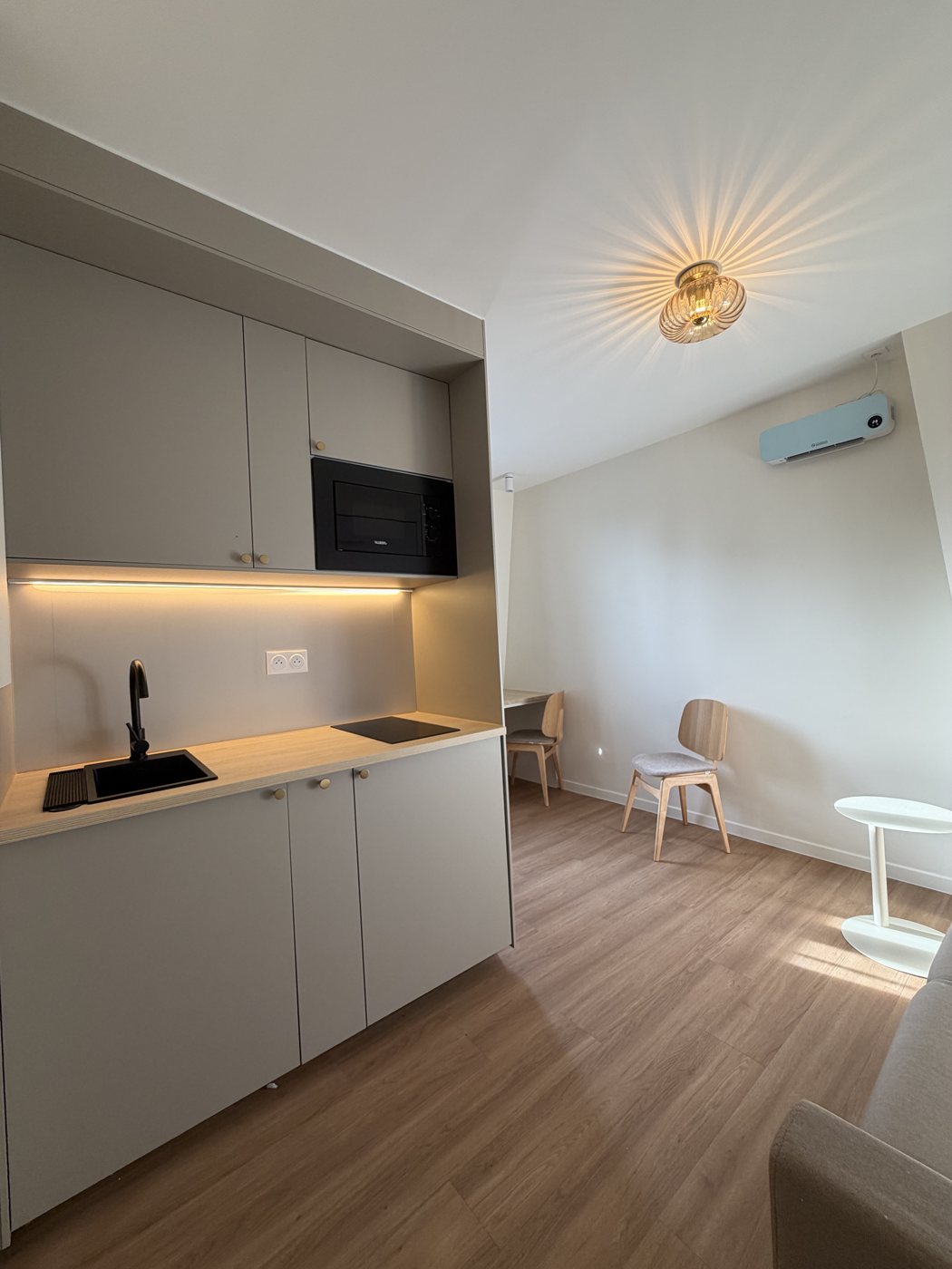 Vue d'ensemble du studio, cuisine et coin repas baignés de lumière